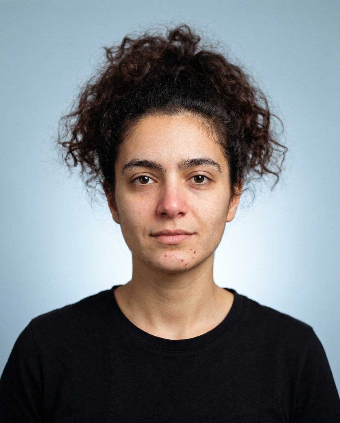 KI-Visualisierung, Ausgangsbild: Frau mit ungestylten, krausen Locken und ungezupften Brauen, frontal vor graublauem Hintergrund